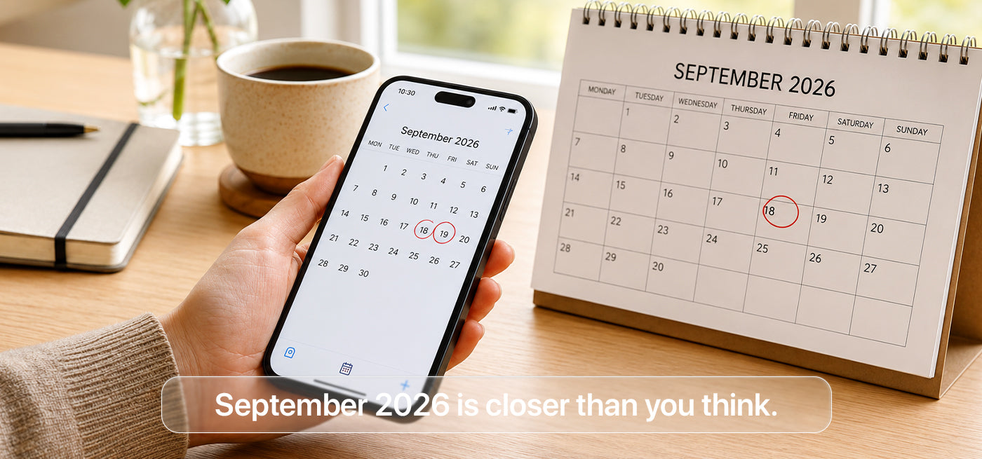 Hand holding iPhone showing September 2026 calendar with circled iPhone 18 launch date next to a desk calendar — UK release date countdown